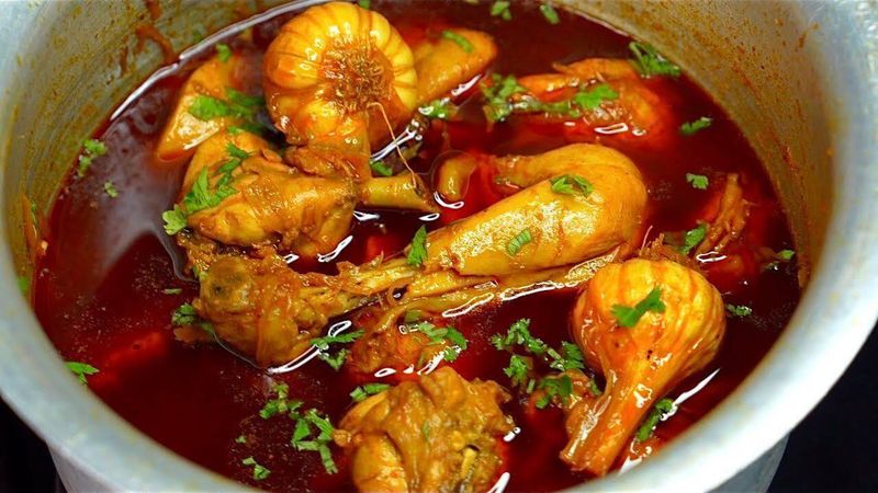 Chicken handi simmering in a deep pot with fresh coriander