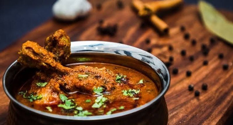 Kadhai chicken in a steel handi with whole spices and bay leaf
